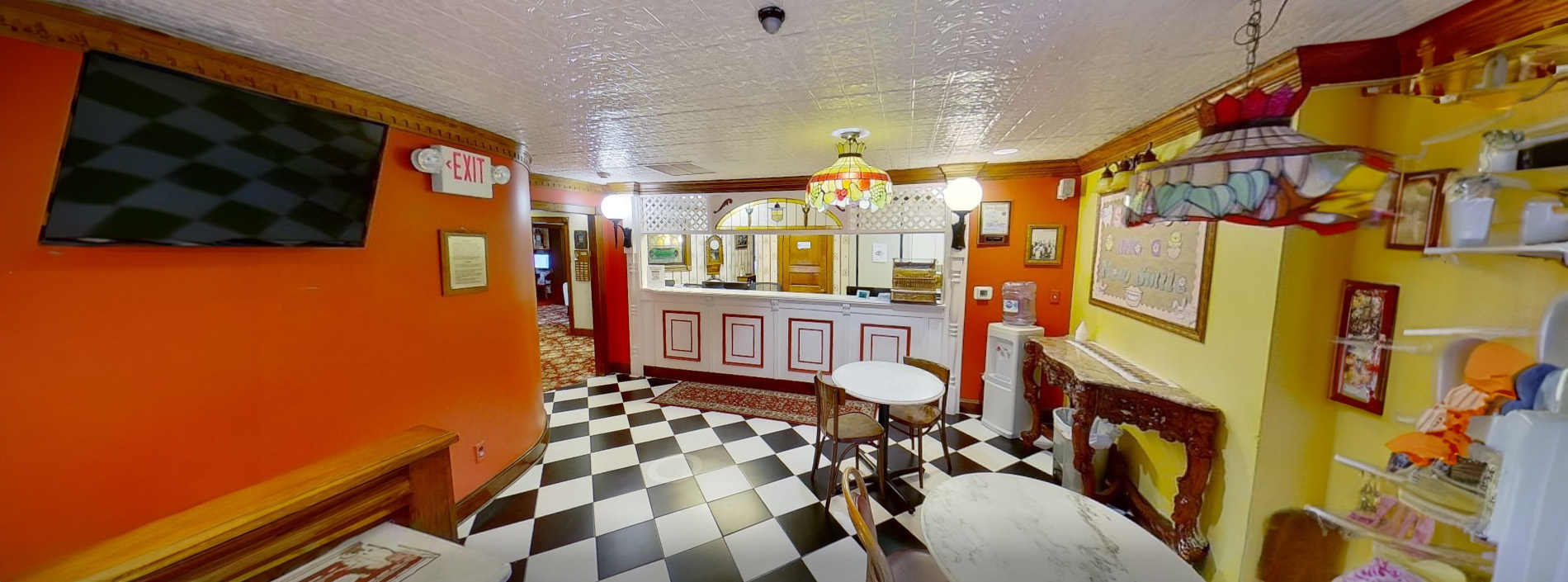 The image depicts the interior of a restaurant with a checkered floor, red walls, and various dining tables and chairs visible.