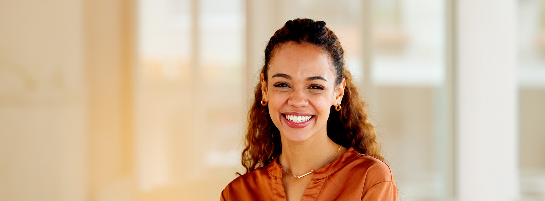 A smiling woman with braided hair posing against a blurred background.