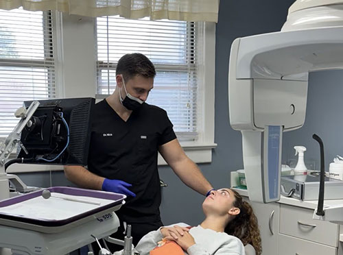 Image  A medical professional assisting a patient during an examination in a dental office setting.